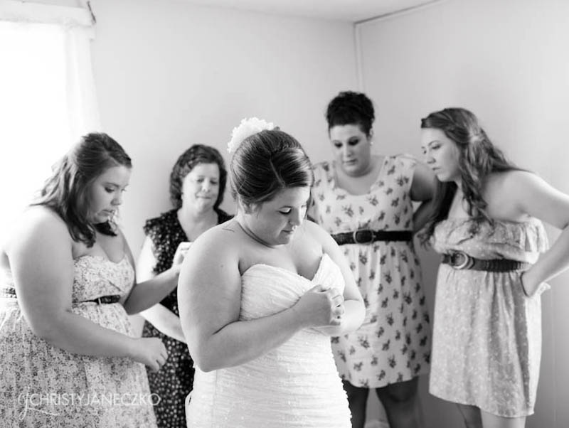 bridesmaids zipping up brides dress