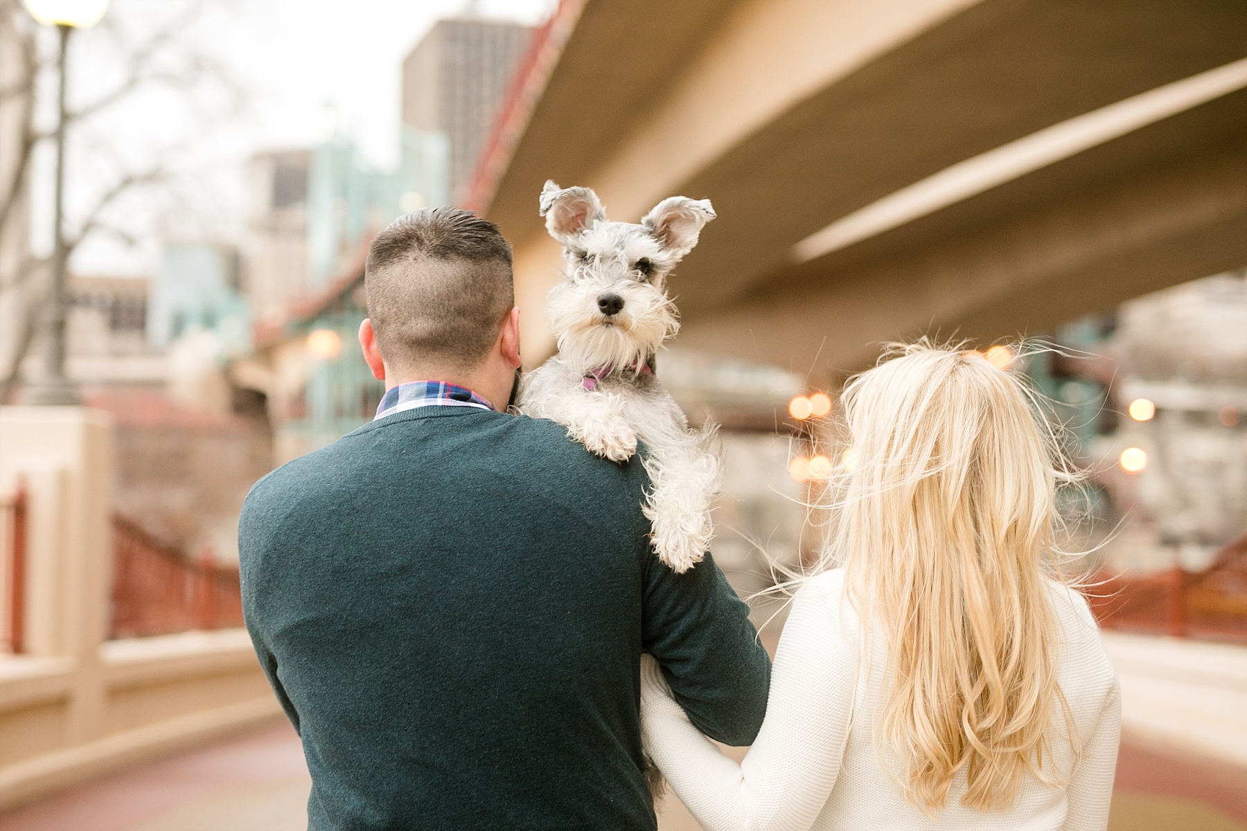 couple under bridge with their dog looking over their shoulder in St. Paul