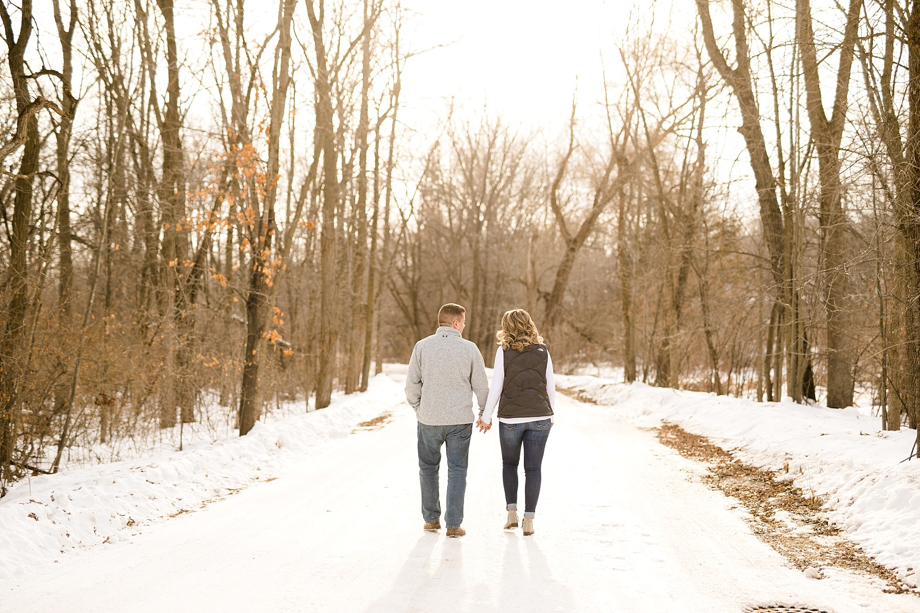 couple walking away down a snow covered road for their engagement photos in Eau Claire, Wisconsin