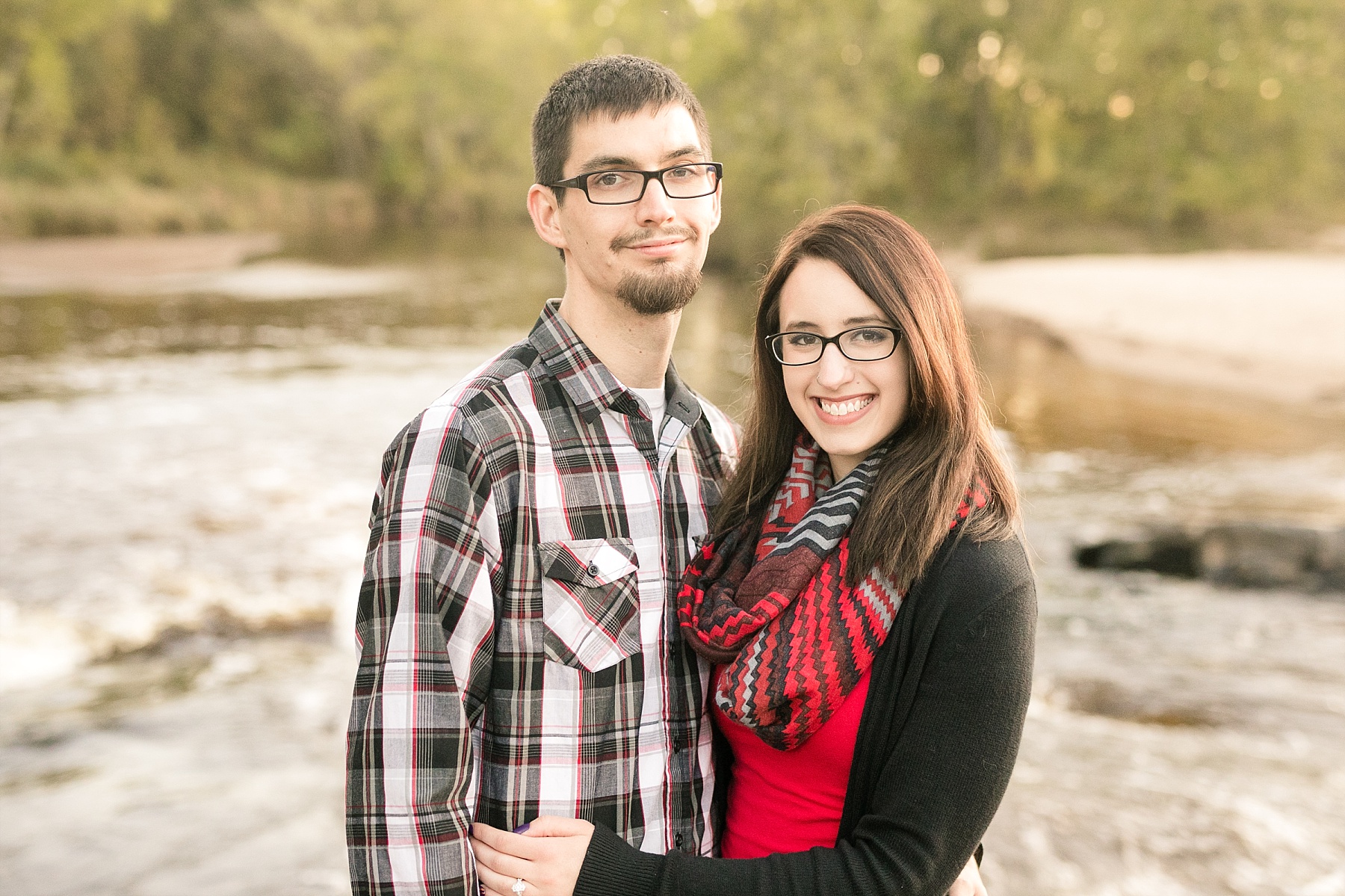 Couple smiling at the camera for engagement photos at Big Falls in Eau Claire.