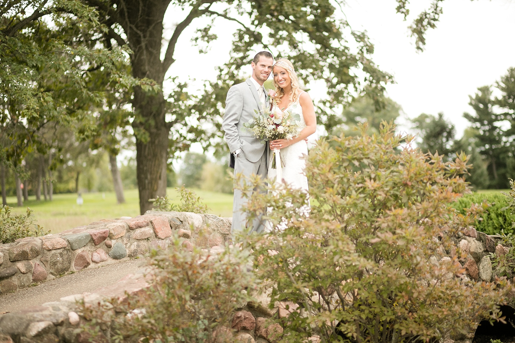 bride and groom smiling on rock bridge at Lake Wissota Golf & Events