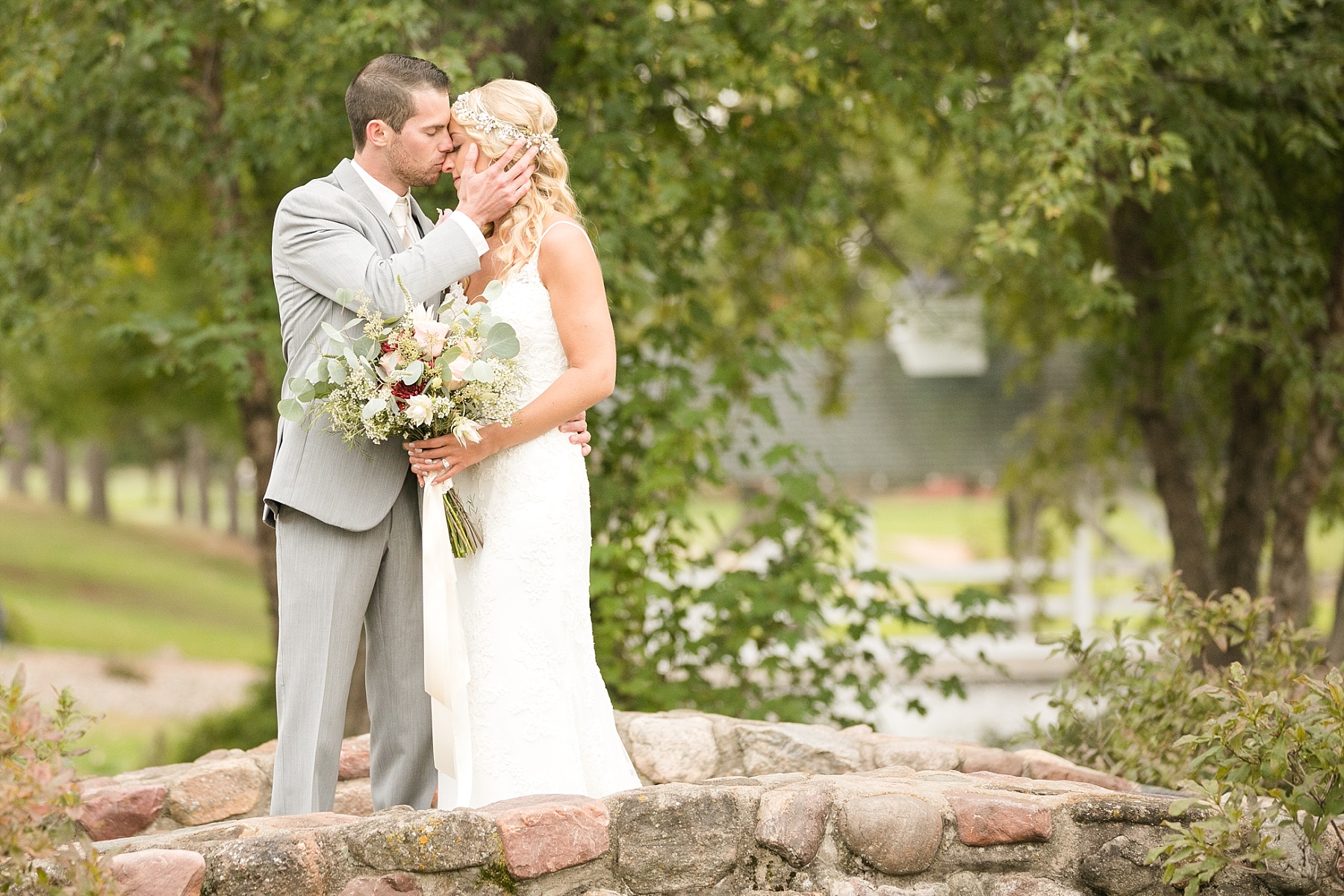 groom kissing brides nose on rock bridge at Lake Wissota Golf & Events