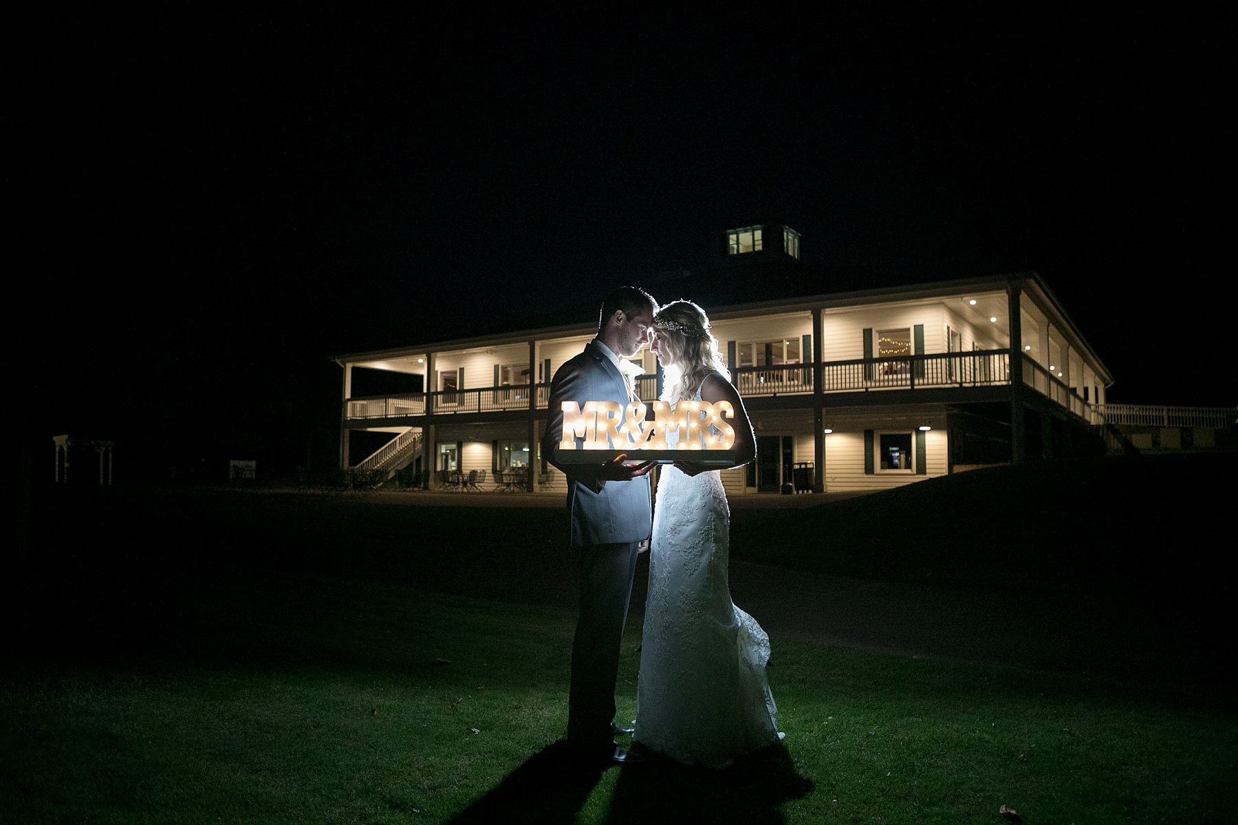 bride and groom at night with lit up mr. and mrs. sign at Lake Wissota Golf & Events
