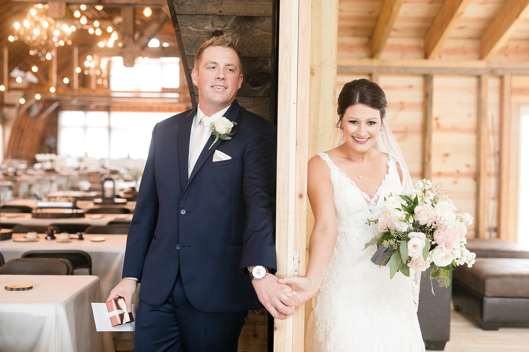 bride and groom touching hands between doors at the barn on stoney hill