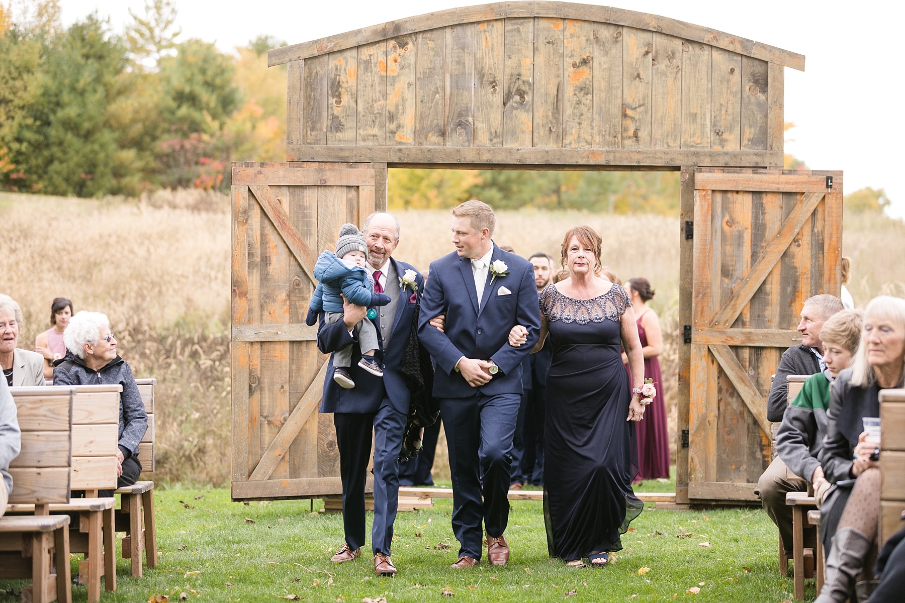 groom with parents and son walking down the aisle at the barn on stoney hill