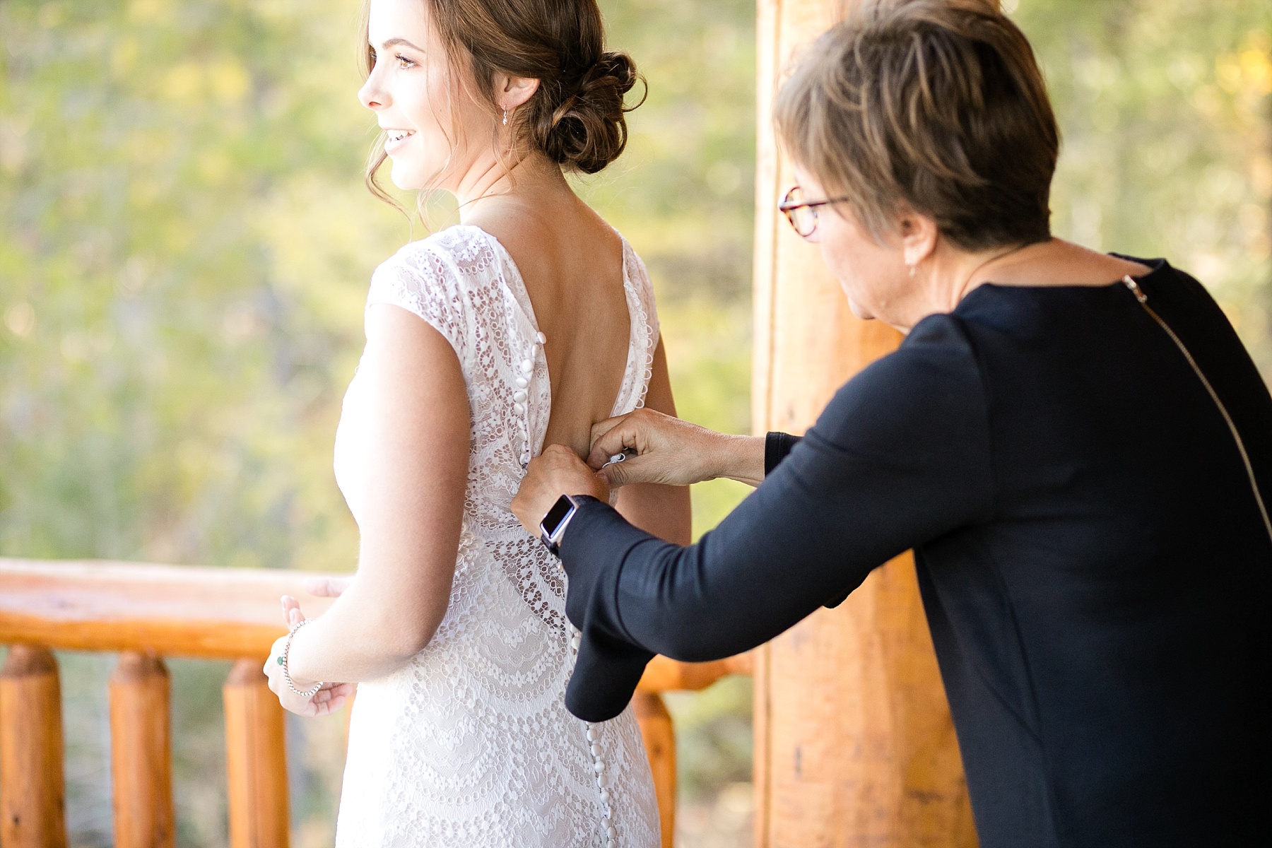 mom helping her daughter into her wedding gown overlooking Glacier National Park