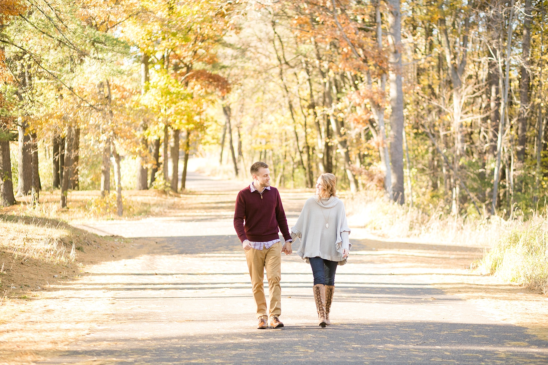 bride and groom walking down a fall road for their chippewa falls engagement photos