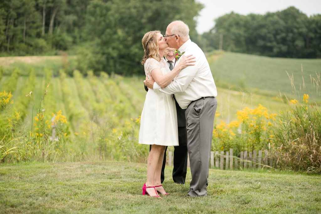 couple kissing during their elopement overlooking a vineyard at cottage winery