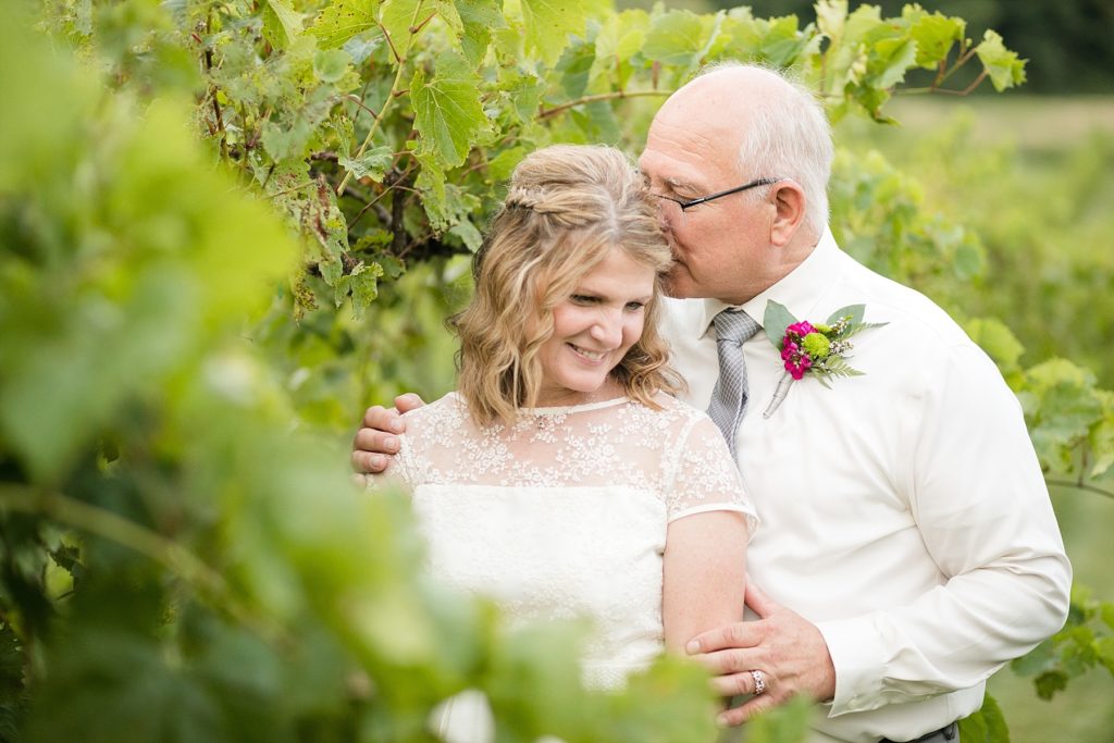 groom kissing bride after eloping in a vineyard in wisconsin.