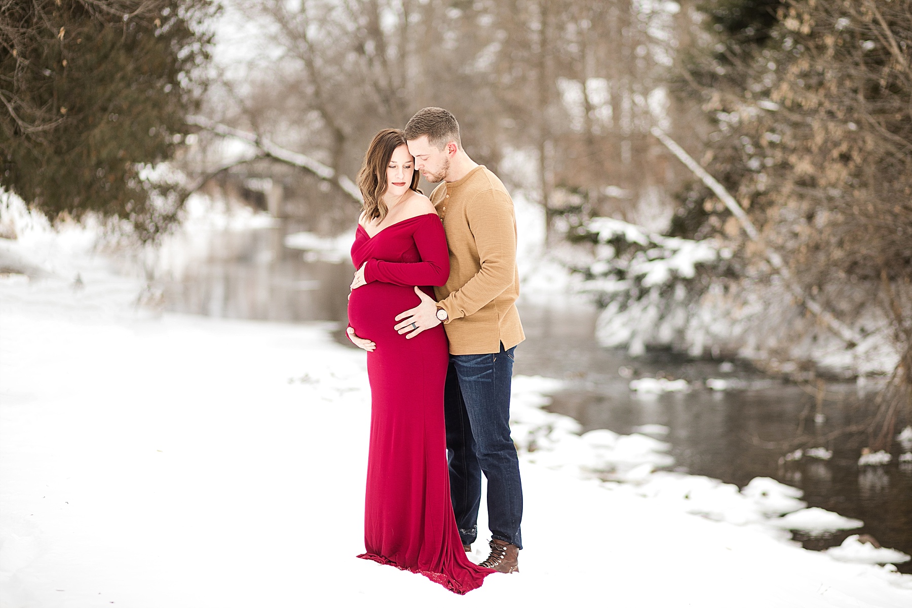 couple on a river bank for their Eau Claire winter maternity photos