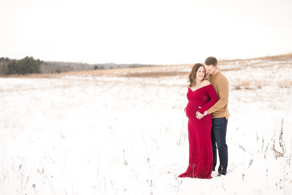 couple at the Ice Age Moraine Trail center in a field smiling for their maternity photos