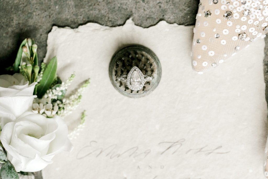 brides ring and wedding invitation on a textured concrete floor