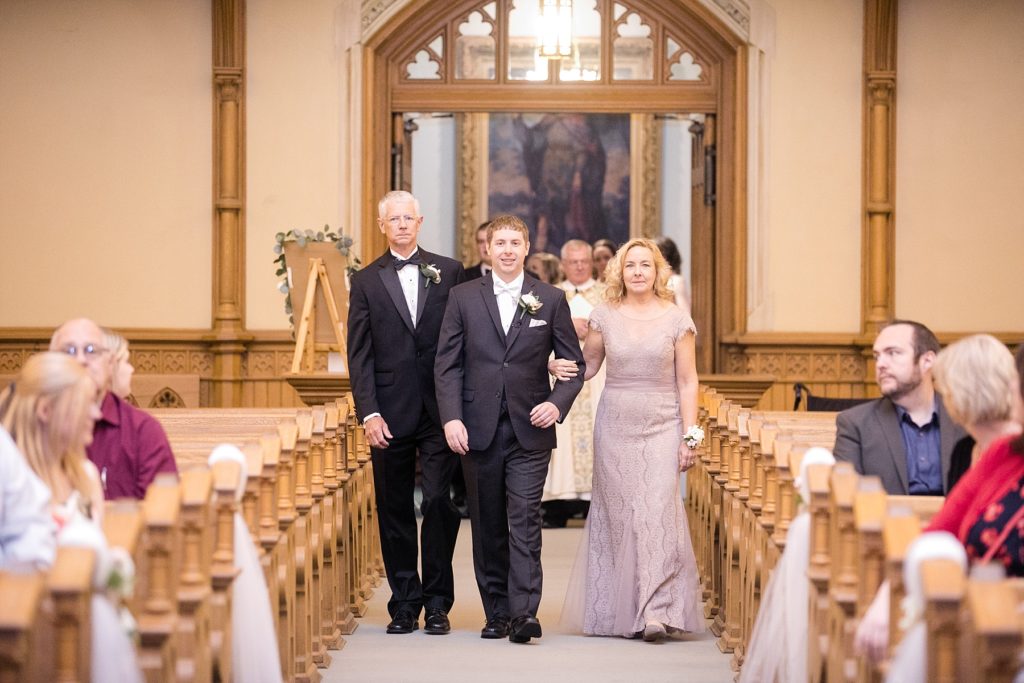 groom walking down the aisle with parents at Wedding at St. Raphael & St. Patrick Cathedral in Dubuque