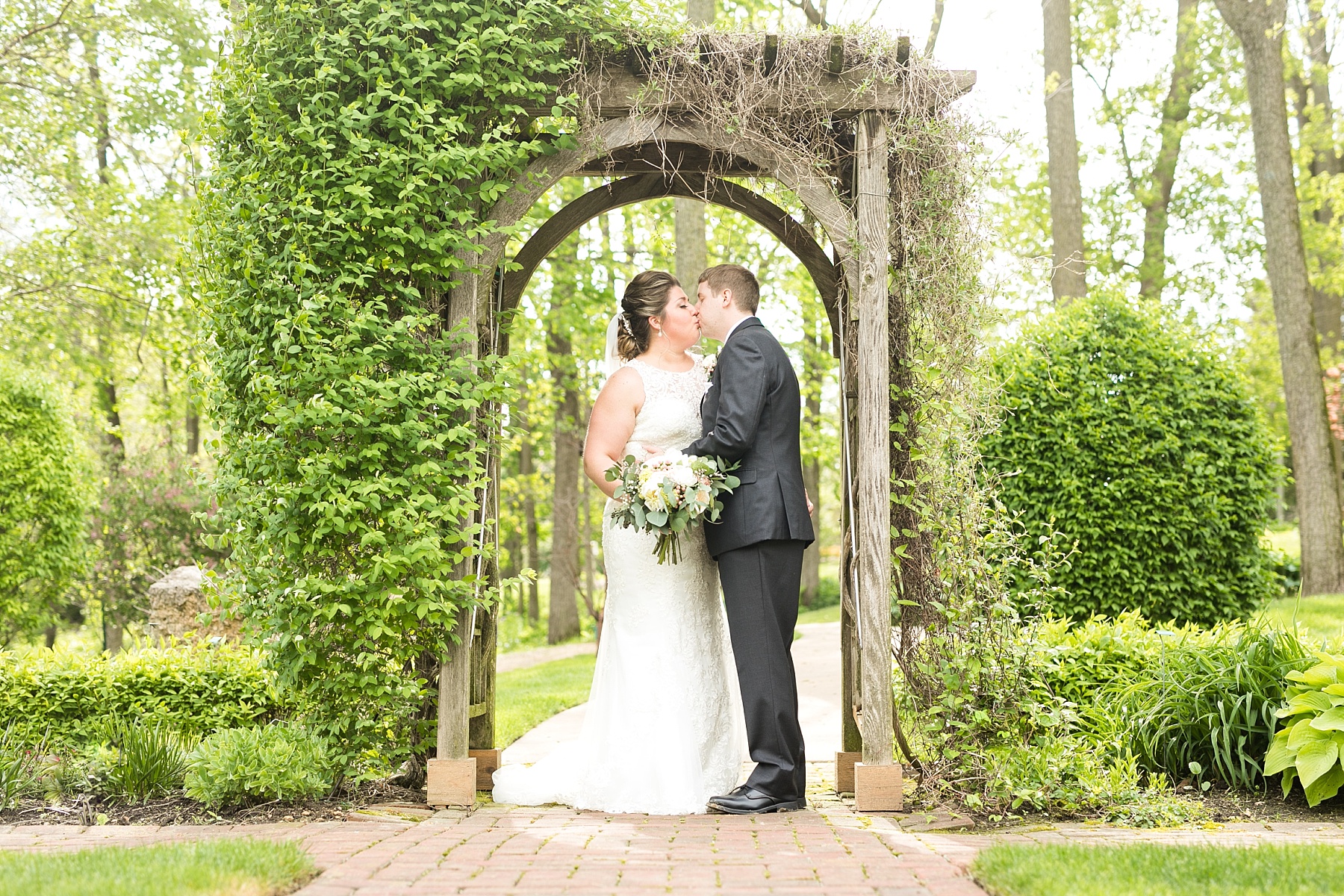 couple kissing under archway at a wedding at the Dubuque Arboretum