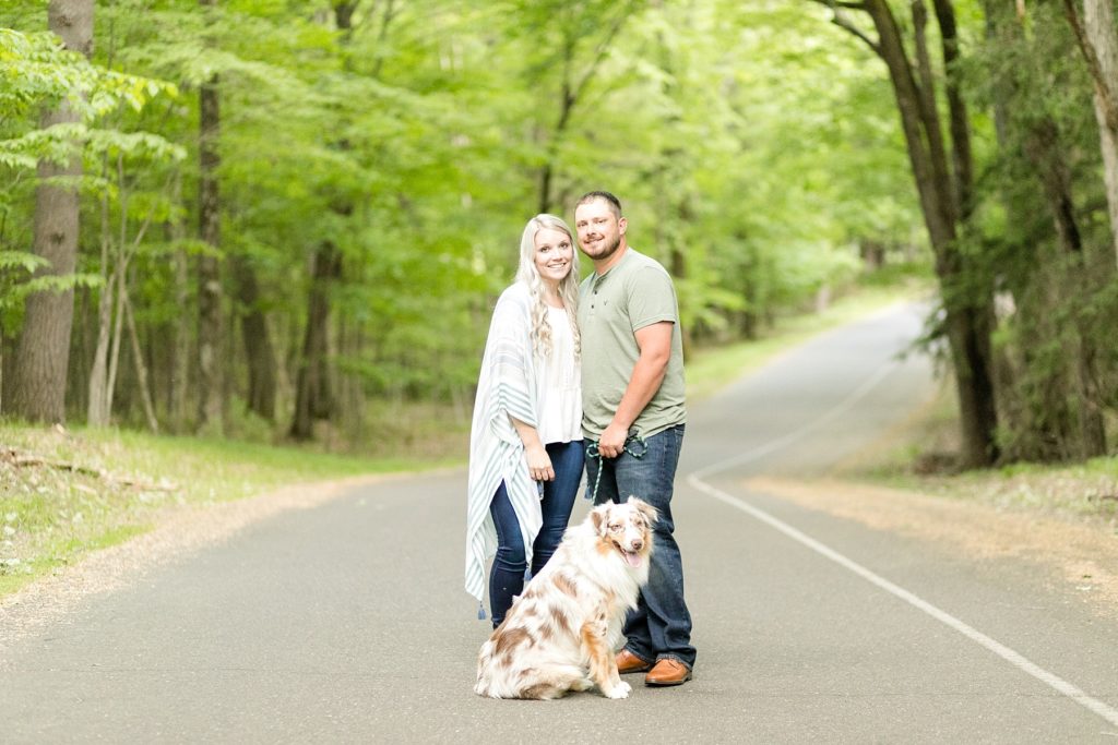 couple with their dog on a road at their engagement session at Brunet Island State Park in Cornell, WI