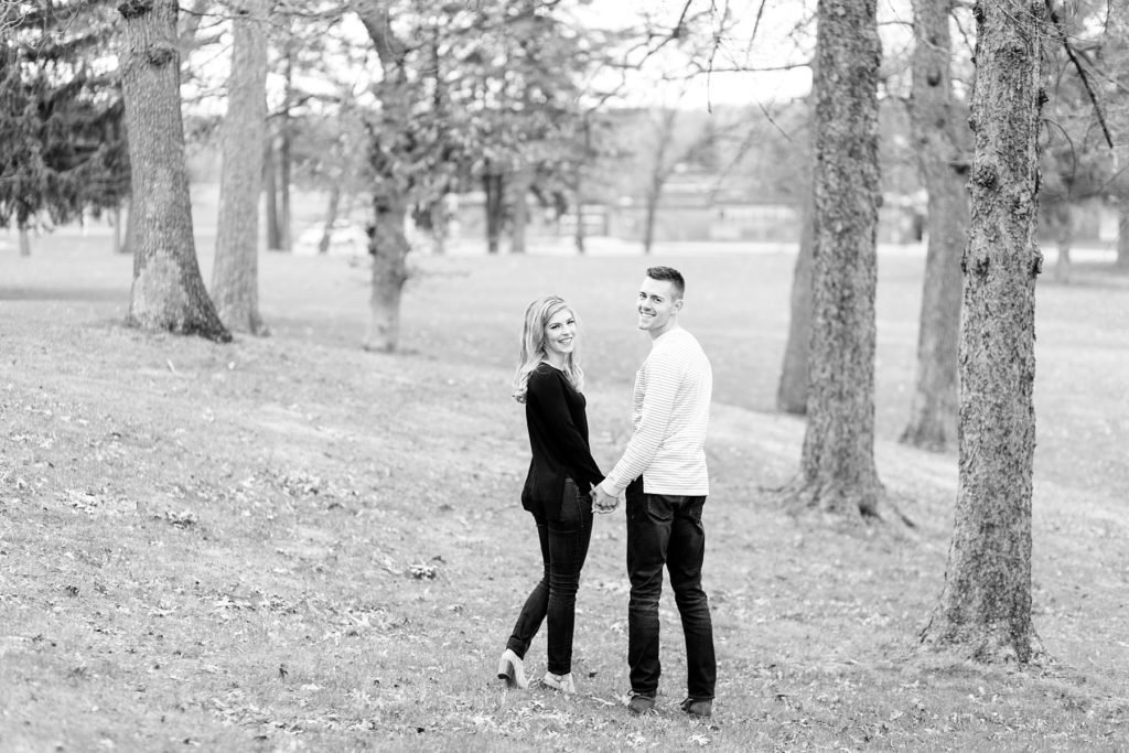 black and white photo of the couple looking back in the middle of pine trees