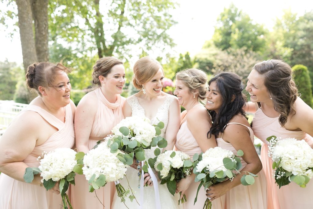 bridesmaids laughing with bride in the center at wedding atThe Florian Gardens in Eau Claire