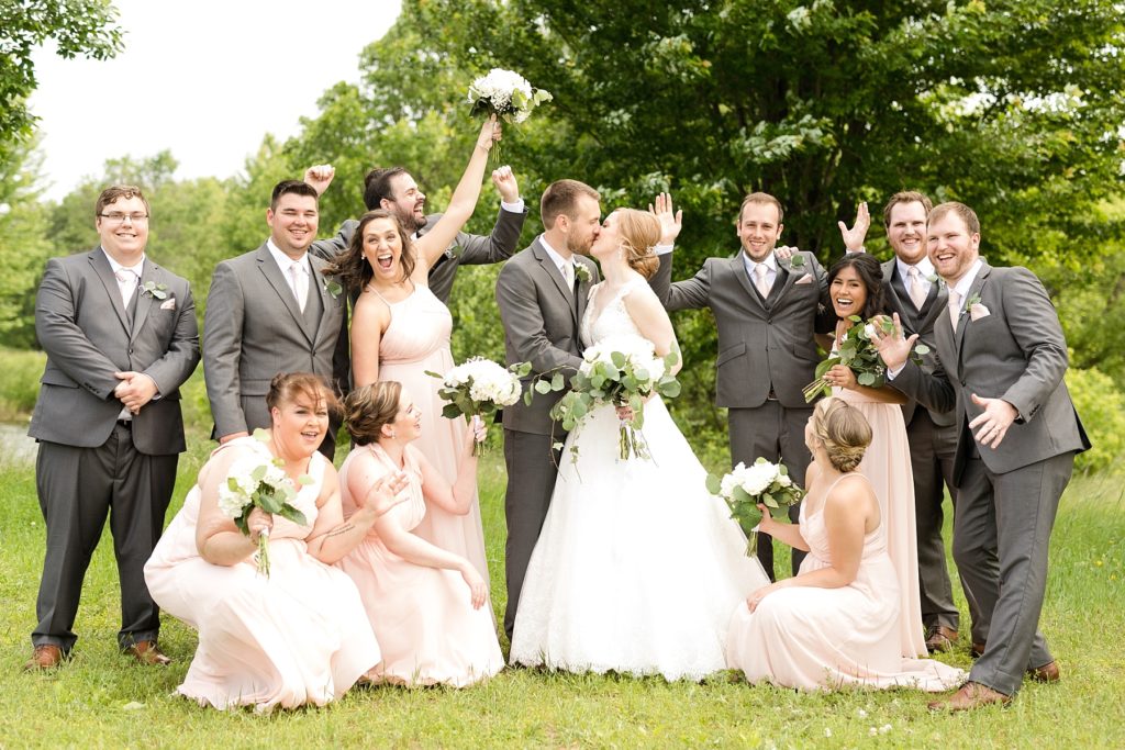 bridal party cheering while bride and groom kiss at wedding atThe Florian Gardens in Eau Claire