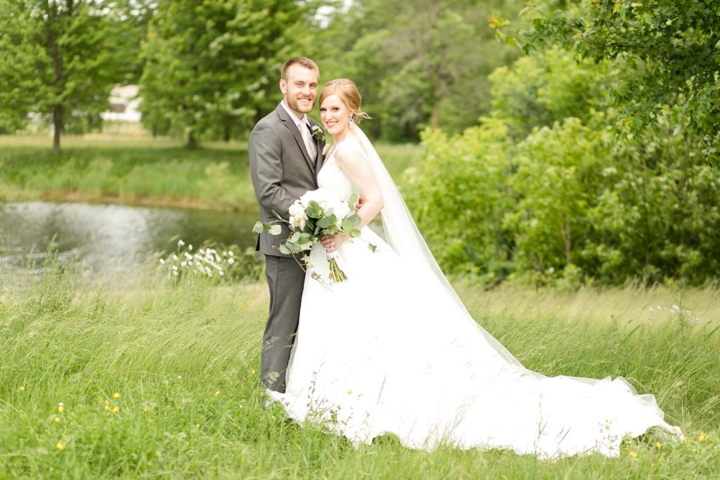 bride and groom infront of a lake at wedding atThe Florian Gardens in Eau Claire