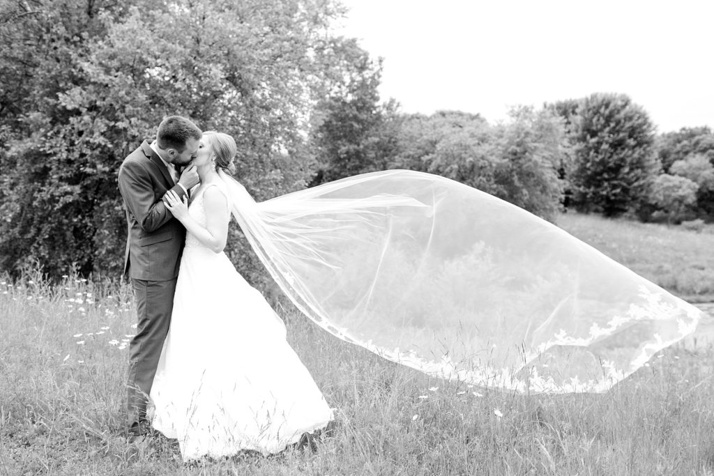 couple with cathedral length veil blowing in the wind at wedding atThe Florian Gardens in Eau Claire
