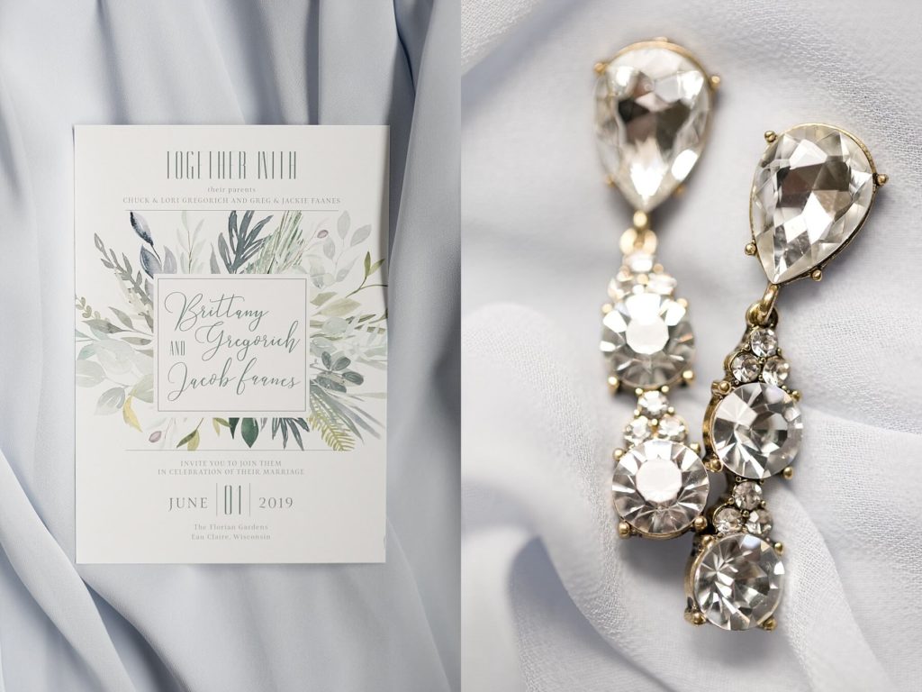 the wedding invitation and brides earrings at the Florian Gardens in Eau Claire
