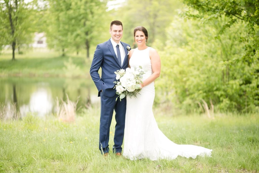 bride and groom smiling at the camera with a lake behind them in Eau Claire