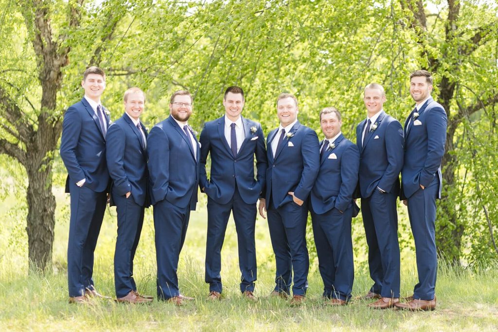 groom and groomsmen smiling at the camera at the Florian Gardens in Eau Claire