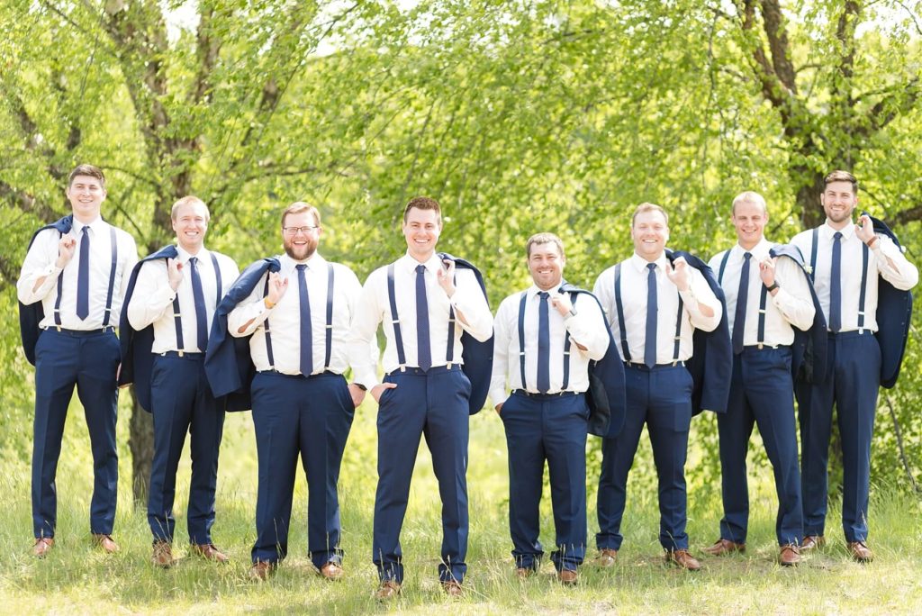 groom and groomsmen with suspenders and jackets off at the Florian Gardens in Eau Claire