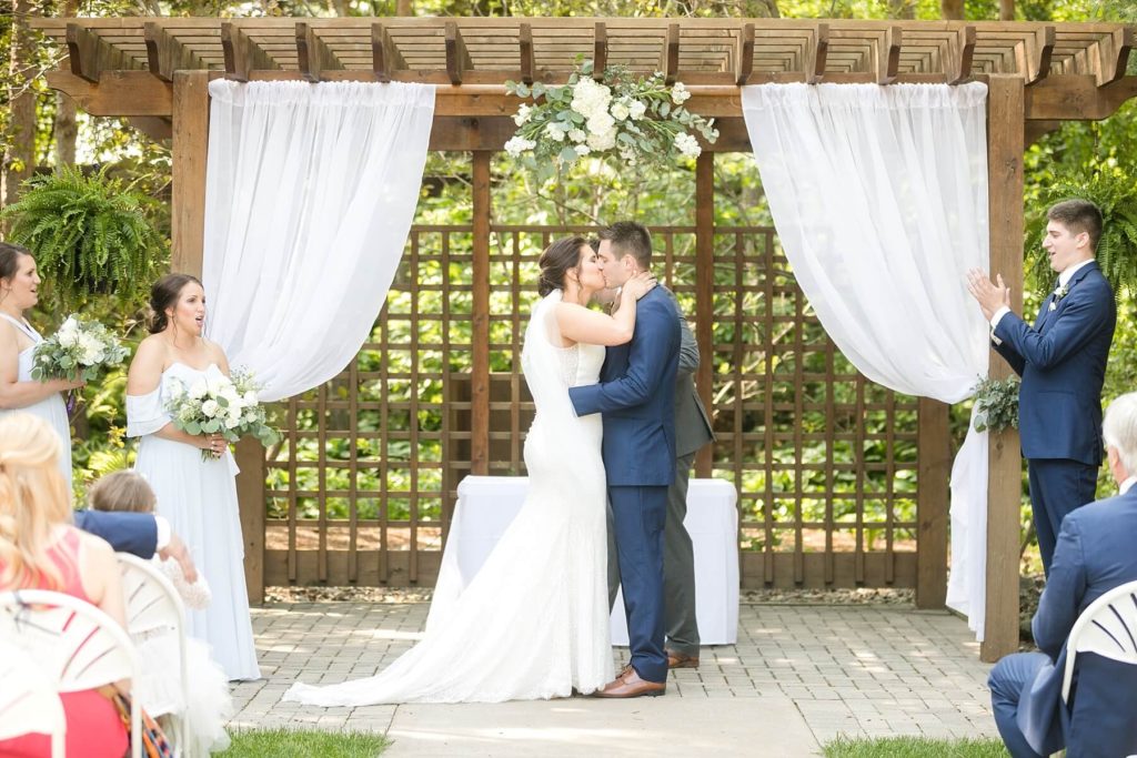 first kiss at the ceremony under the pergola in the garden at at the Florian Gardens in Eau Claire