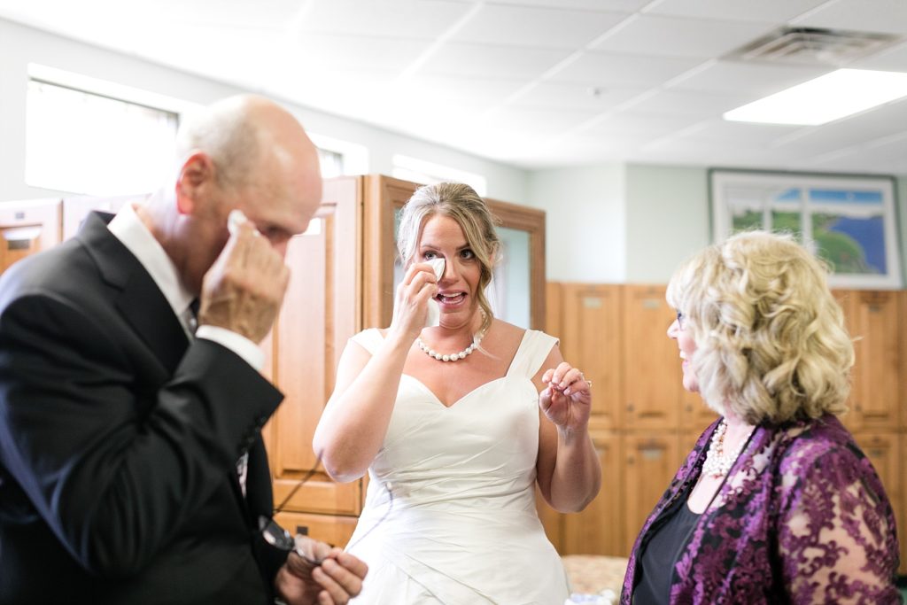 bride and father wipe tears from their eyes while mom smiles at the Eau Claire Golf & Country Club