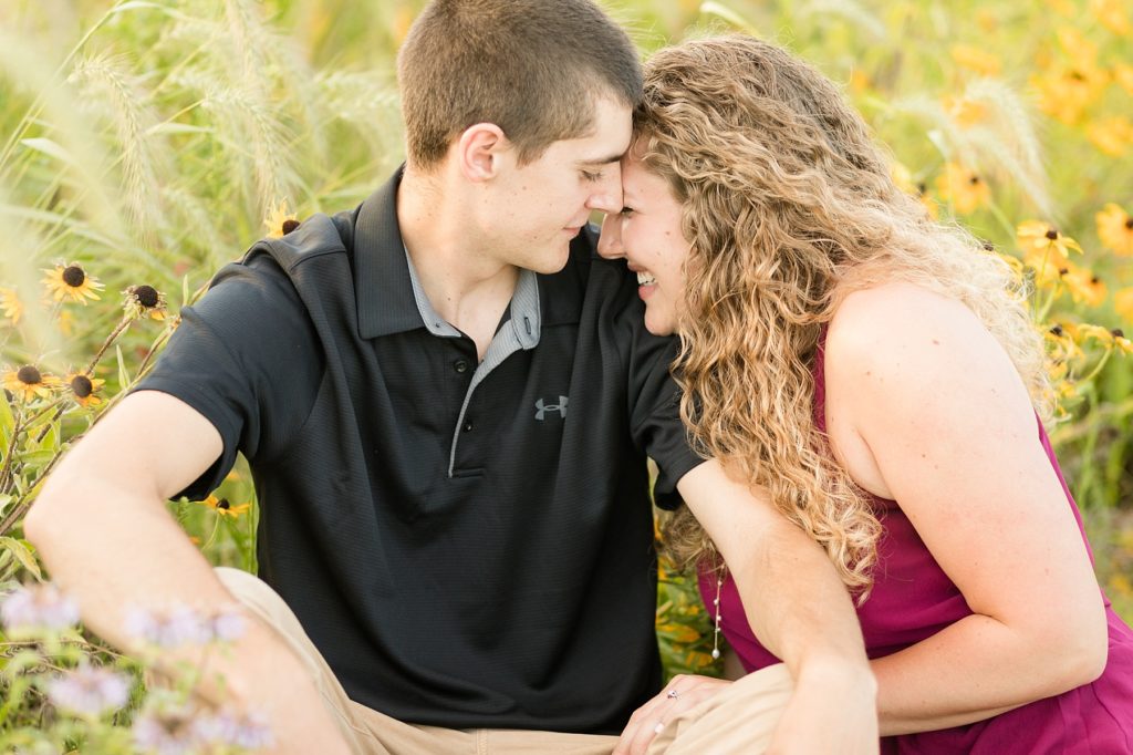 couple cuddling a field of wildflowers for their engagement session in Bloomer 