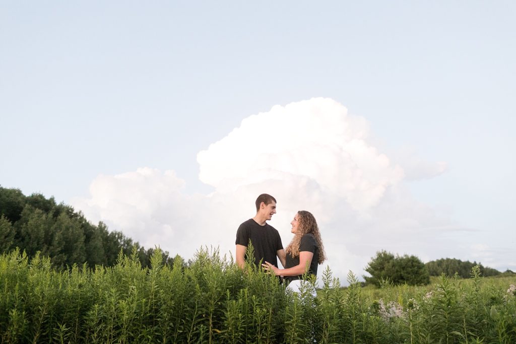 couple in a field at the Dave Obey Nature Center with a thunderhead behind them in the sky