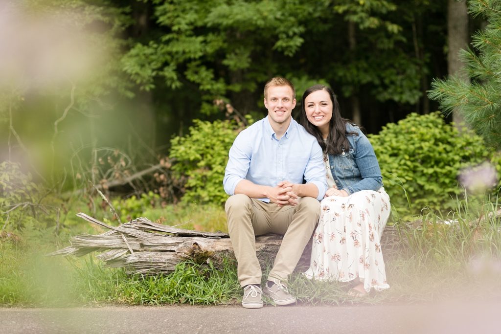 couple sitting on a log in Brunet Island State Park for their engagement pictures