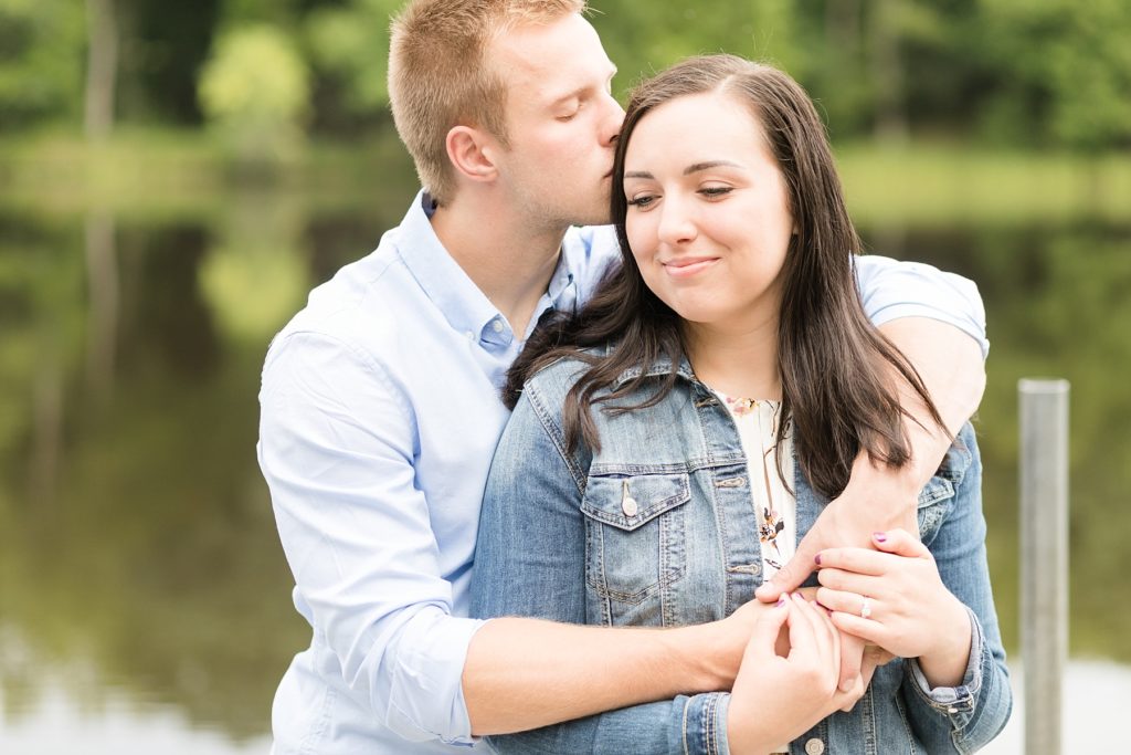 guy kissing a girls temple on a dock in Brunet Island State Park for their engagement pictures