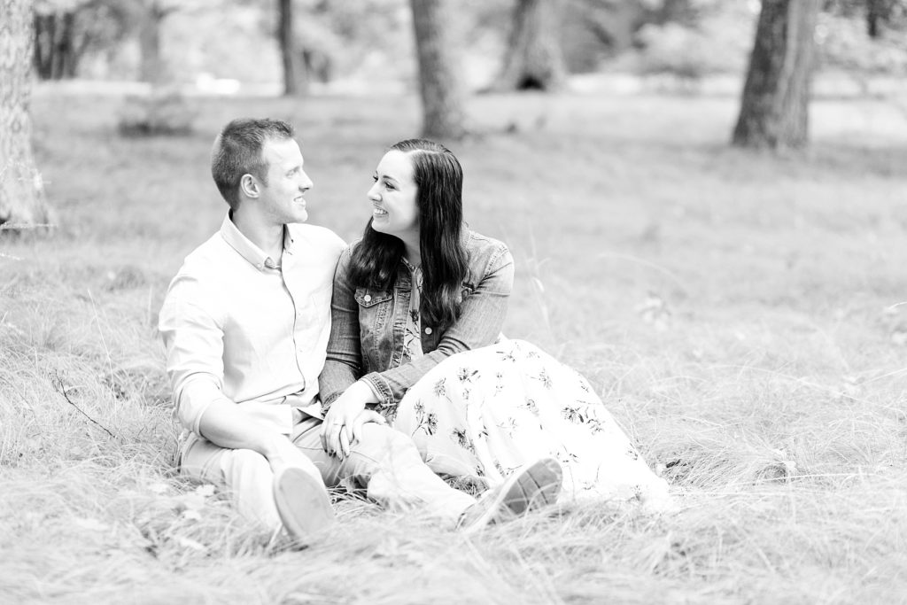 couple sitting in grass in Brunet Island State Park for their engagement pictures