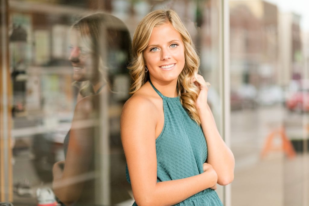 girl leaning against a glass wall for her Chippewa Falls senior photos