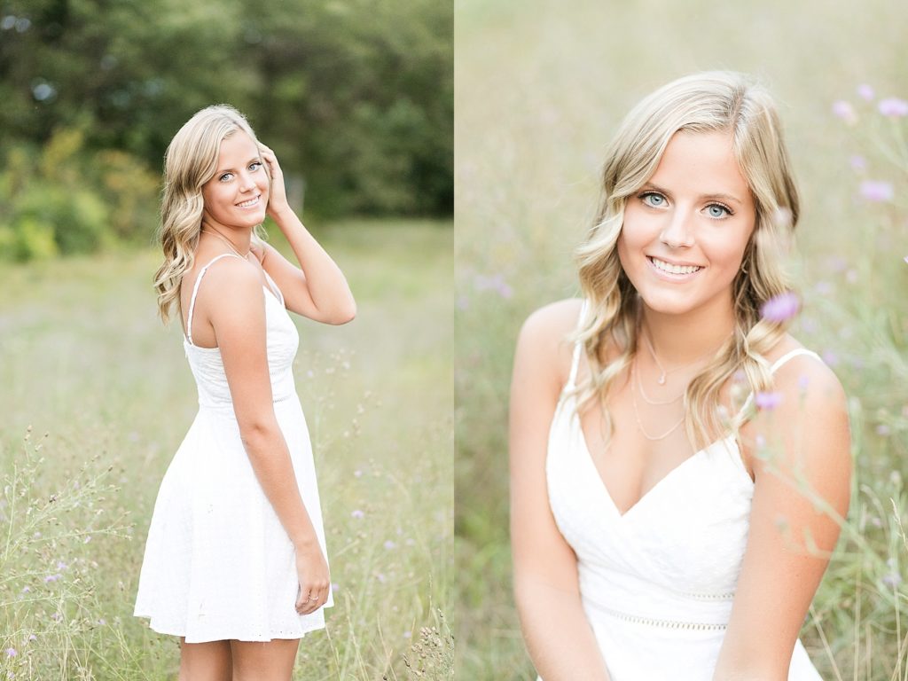 girl looking over her shoulder in a white dress smiling and sitting in a field of purple flowers in Chippewa Falls for her senior photos