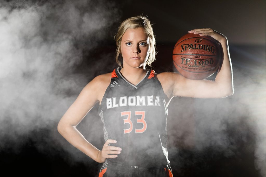 girl in the Bloomer High School gym wearing a Bloomer Blackhawks basketball uniform and holding a basketball with fog rolling in over the photo