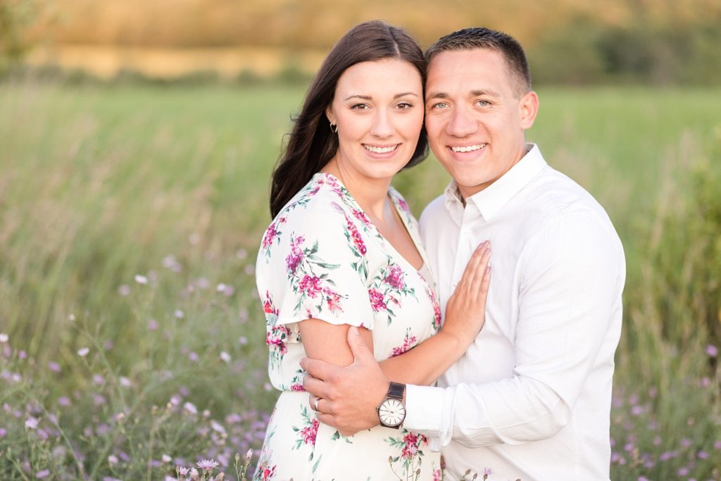 couple in a field of purple flowers looking at the camera for their Eau Claire anniversary session