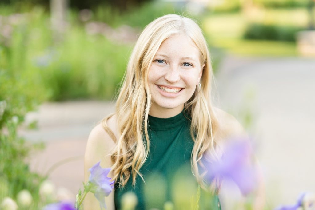 girl in forest green top with blonde hair smiling at camera for her Thorp WI Senior photos