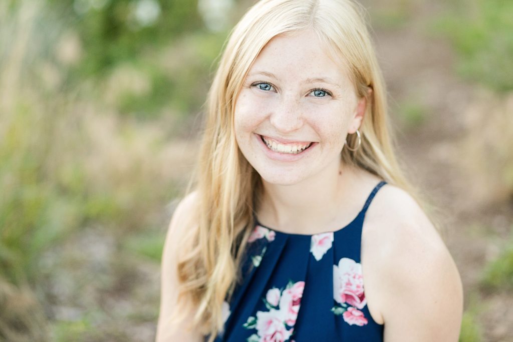 girl in a close up photo in a floral blue dress smiling for her Thorp WI Senior photos