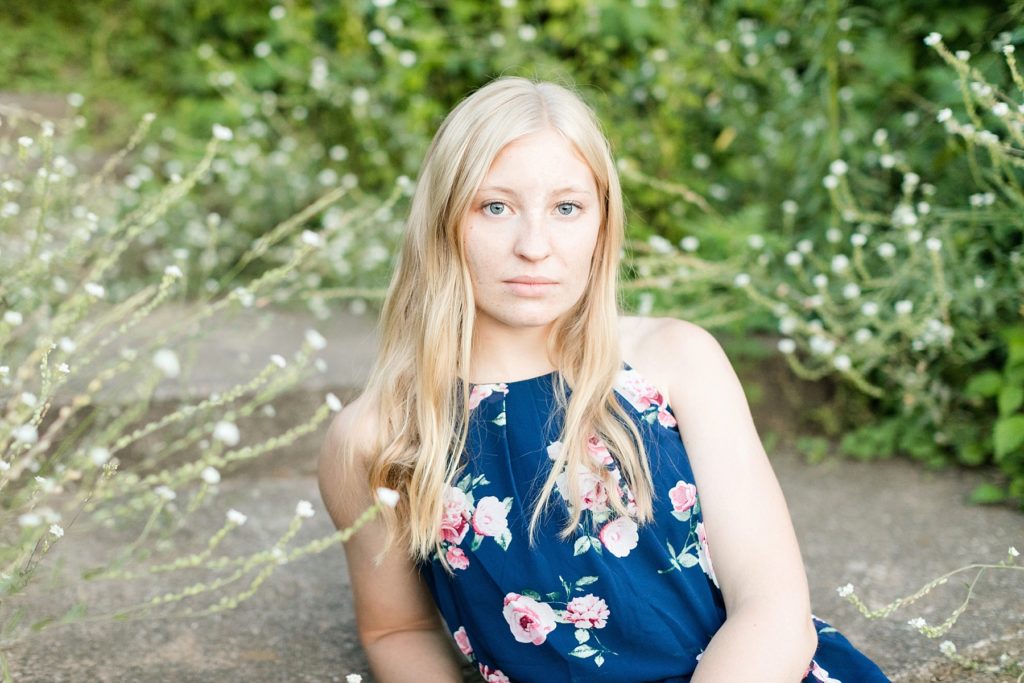 serious photo of girl for her Thorp WI Senior photos in a blue dress surrounded by white flowers