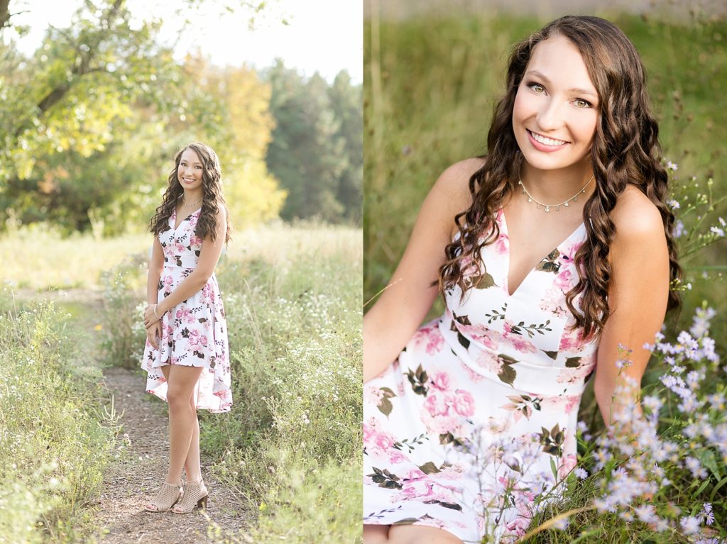 girl in a pink and white floral dress in tall grass and flowers for her Lake Wissota State Park senior pictures