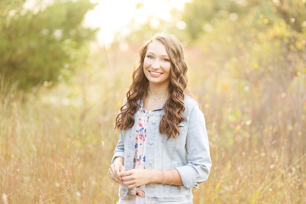 girl in a light jean jacket smiling at the camera for her Cadott Senior pictures