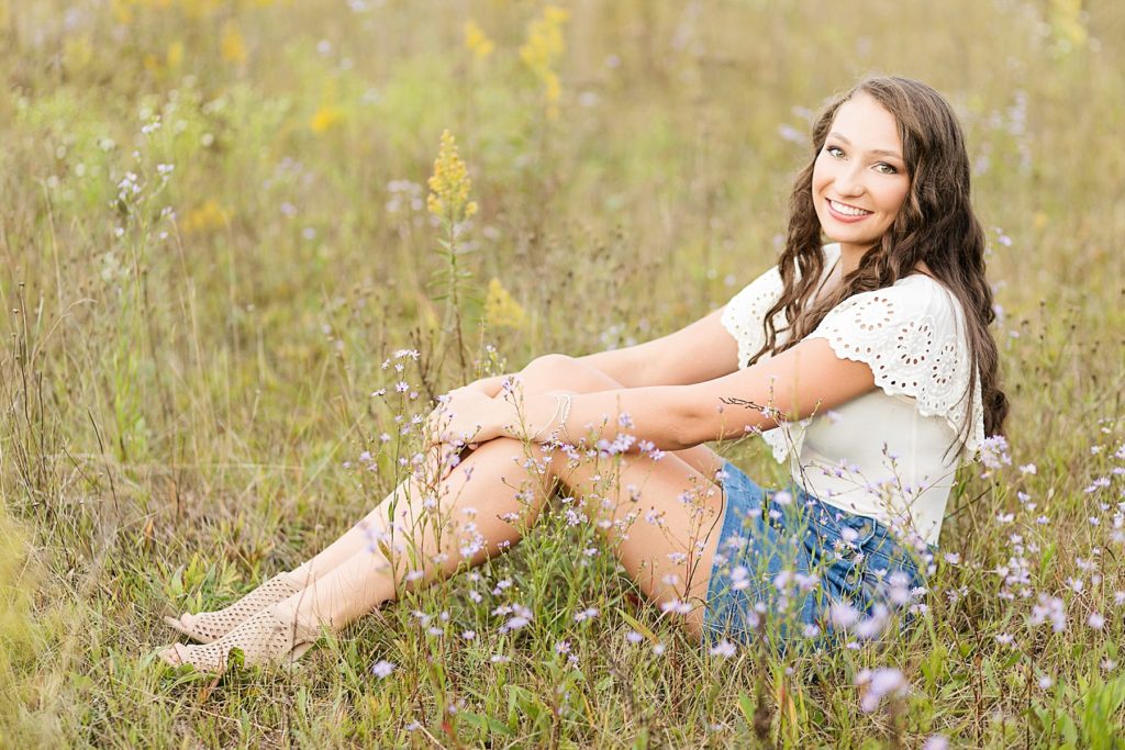 girl in a skirt and white top in a field of flowers for her Cadott senior pictures
