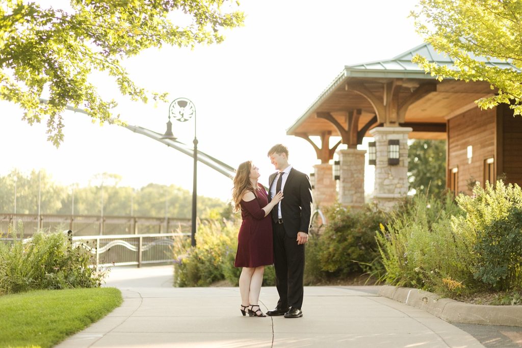 couple in Phoenix Park in downtown Eau Claire for their engagement photos with a bridge and pavilion in the background