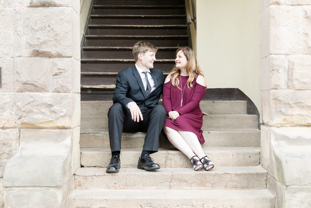 couple sitting on some stone stairs in downtown Eau Claire for their engagement session
