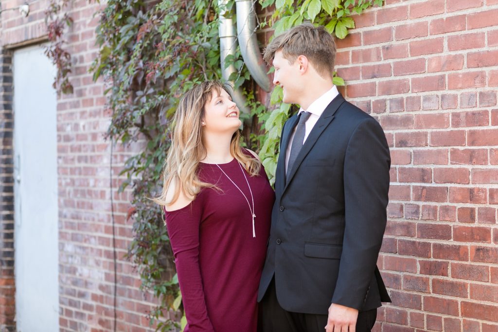 couple standing by a brick wall covered with vines in downtown Eau Claire for their engagement session