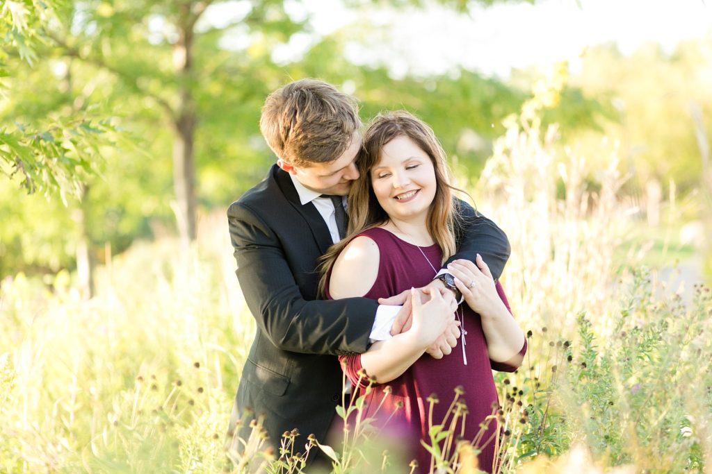 couple hugging in tall grass at Phoenix park in Eau Claire for their engagement session
