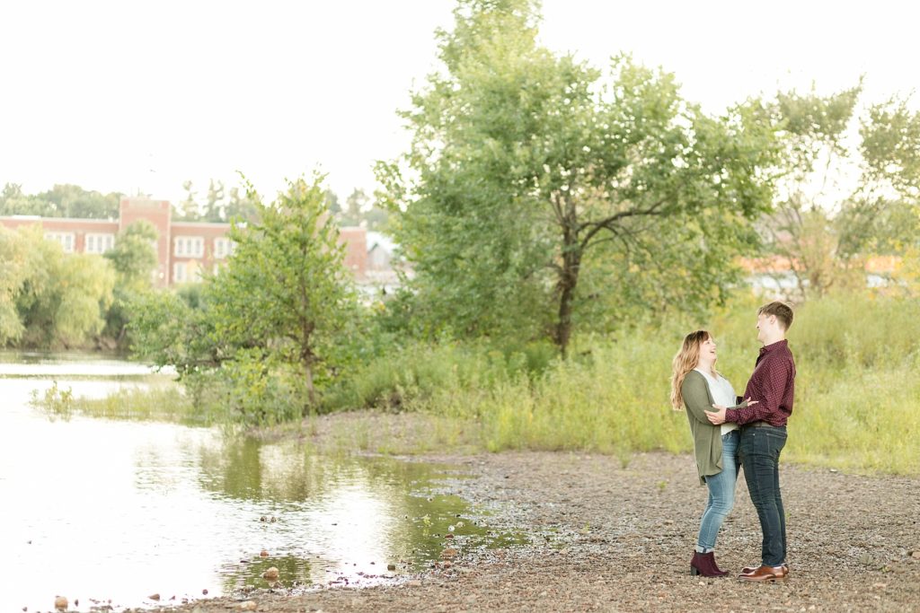 couple laughing and talking on a riverbed in Eau Claire for their engagement photos
